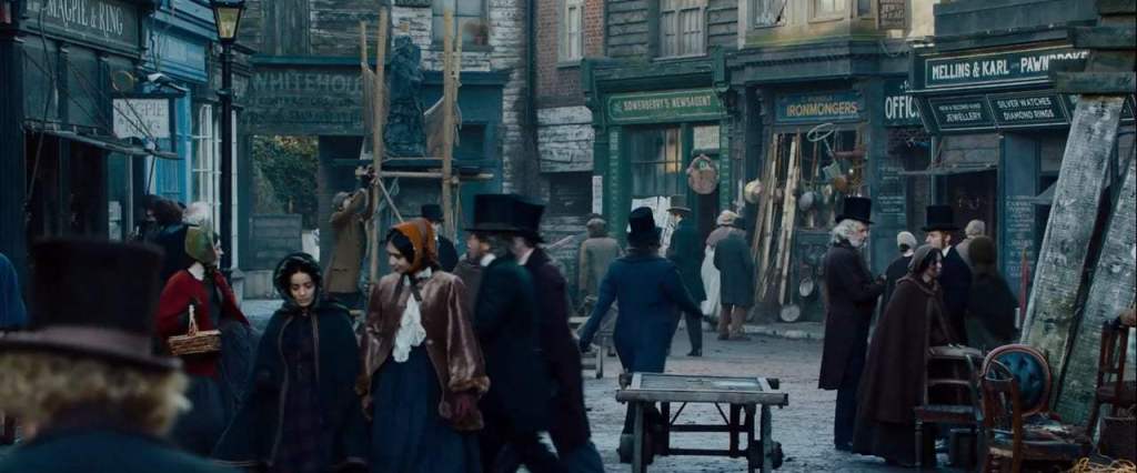 A widescreen scene from the film featuring a busy Victorian street of shops.